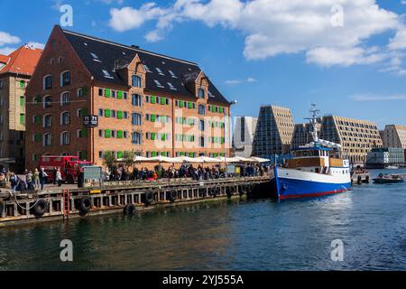 Am 29. April 2023 laufen die Menschen in Kopenhagen, Dänemark, vorbei an bunten Fassaden und alten Schiffen entlang des Nyhavn-Kanals. Stockfoto