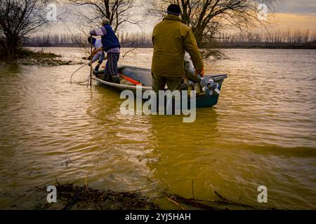 Menschen, die auf Bootsfahrt auf dem breiten Fluss gehen, der Waldboden in der Nähe der Küste, Landschaft mit Wasserfluten überschwemmt hat. Stockfoto