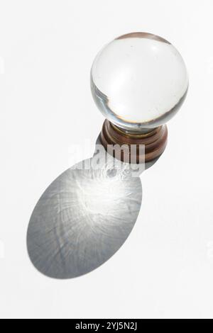 Kristallkugel auf weißem Hintergrund mit projiziertem Schatten, inspirierendem abstraktem Bild Stockfoto