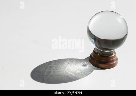 Kristallkugel auf weißem Hintergrund mit projiziertem Schatten, inspirierendem abstraktem Bild Stockfoto
