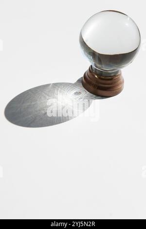 Kristallkugel auf weißem Hintergrund mit projiziertem Schatten, inspirierendem abstraktem Bild Stockfoto