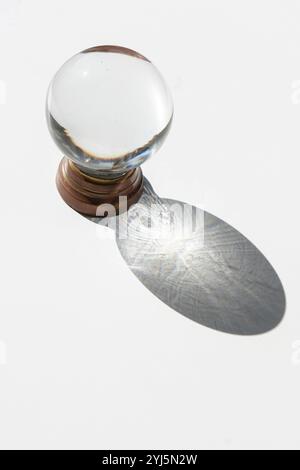 Kristallkugel auf weißem Hintergrund mit projiziertem Schatten, inspirierendem abstraktem Bild Stockfoto