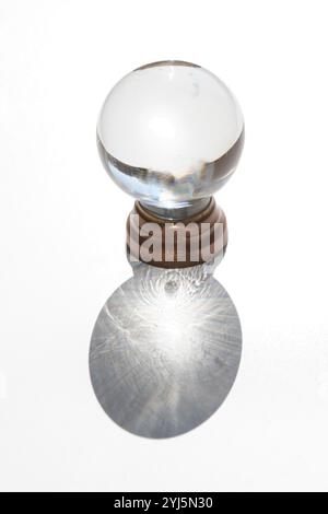 Kristallkugel auf weißem Hintergrund mit projiziertem Schatten, inspirierendem abstraktem Bild Stockfoto