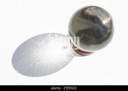 Kristallkugel auf weißem Hintergrund mit projiziertem Schatten, inspirierendem abstraktem Bild Stockfoto