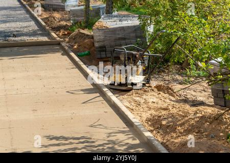 Eine Verdichtungsmaschine arbeitet auf neuem Beton in einem Gartenbereich. Stockfoto