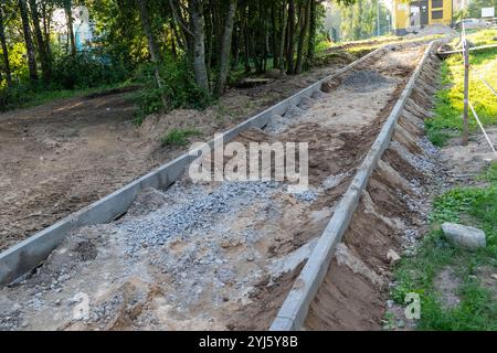 Die Arbeiter bauen im Wald einen Weg mit Kies und Beton. Stockfoto