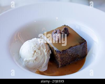 Kandierte Pekannüsse runden einen klebrigen Toffee-Pudding ab, der mit Vanilleeis serviert wird. Die traditionelle Version des Gerichts ist ein beliebtes britisches Dessert. Stockfoto