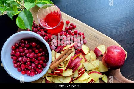 Rezepte für Weihnachten und Feiertage, Glühwein und saisonales Kochkonzept mit geschnittenen roten Äpfeln, Haufen Preiselbeeren und Zimtstangen Stockfoto