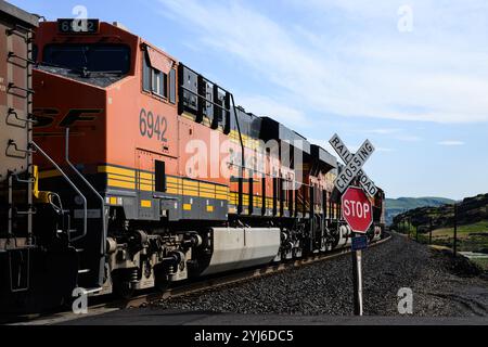 Dallesport, WA, USA - 23. April 2024; BNSF-Güterzug passiert Bahnüberquerung Stoppschild in Nahaufnahme Stockfoto