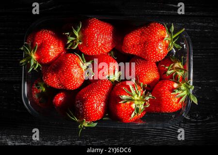 Erdbeerpaket auf schwarzem Holzhintergrund, Draufsicht Stockfoto