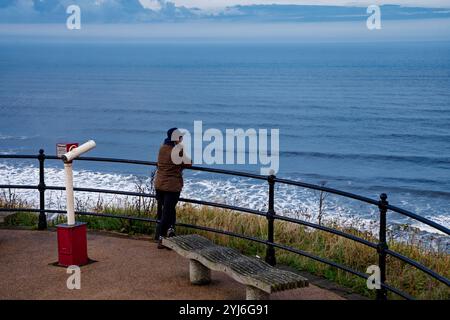 Frau, die aus Sicht aufs Meer schaut, Saltburn. Stockfoto