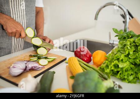 Eine Person hackt gekonnt Gurken und Zwiebeln auf einem Schneidebrett, umgeben von lebhaftem Gemüse wie Salat, Paprika und Mais in einem sonnigen KI Stockfoto