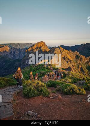 Wanderer auf einem Bergpfad bei Sonnenaufgang, umgeben von zerklüfteten Gipfeln und warmem Morgenlicht, Madeira. Stockfoto