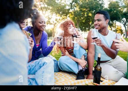 Freunde Dinner, Gruppe von Leuten, die mit Wein außerhalb der Stadt bei Picknick-Party feiern. Junge Freunde essen und trinken zusammen Stockfoto