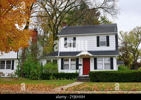 Wheaton, Illinois, USA. Blätter sammeln sich auf dem vorderen Rasen eines zweistöckigen Einfamilienhauses in der Vorstadt an, mit voller Herbstzeit. Stockfoto