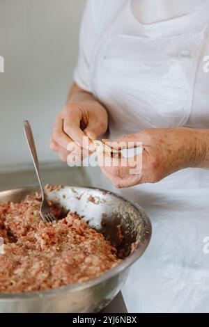 Traditionelle Teigtaschen mit Hackfleischfüllung, die den Teig durch die Hände Formen, für authentische Küche Stockfoto
