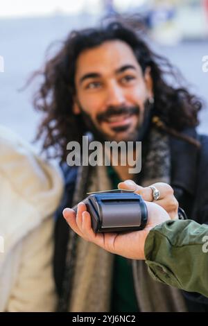 Straßenverkäufer, der kontaktlose Zahlungen von Touristen über POS-Terminal akzeptiert Stockfoto