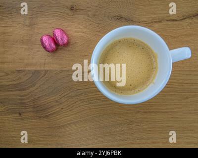 Zwei Schokoladen-ostereier und eine Kaffeetasse auf Eichengrund Stockfoto