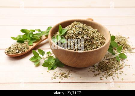 Getrockneter Oregano in Schüssel, Löffel und grüne Blätter auf Holztisch Stockfoto