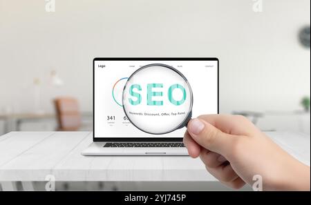 Die Lupe hebt SEO auf dem Laptop-Bildschirm hervor und symbolisiert damit Optimierung und Forschung zur Verbesserung der Website-Performance und Suchmaschinenvisibili Stockfoto