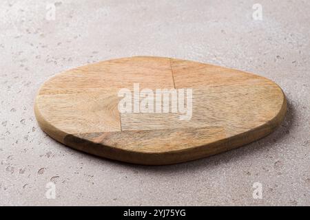 Leeres Schneidebrett aus Holz auf einem beigefarbenen Steintisch, Modell für kreatives Design Stockfoto