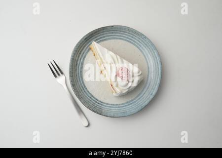 Ein kleiner japanischer Erdbeer-Shortcake und eine kleine Gabel auf einem stilvollen japanischen Teller auf einem weißen Tisch. Stockfoto