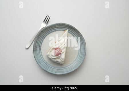 Ein kleiner japanischer Erdbeer-Shortcake und eine kleine Gabel auf einem stilvollen japanischen Teller auf einem weißen Tisch. Stockfoto