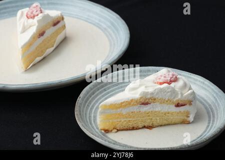 Kleine japanische Erdbeer-Shortcakes auf zwei stilvollen japanischen Tellern, jeweils auf einem schwarzen Tuch auf einem weißen Tisch. Stockfoto