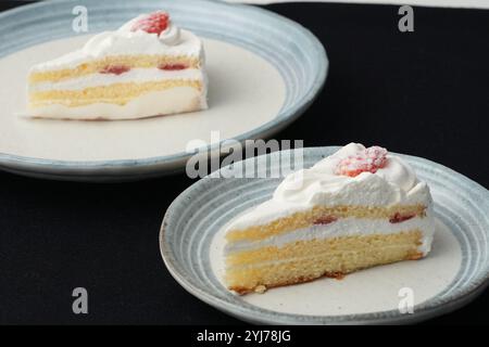 Kleine japanische Erdbeer-Shortcakes auf zwei stilvollen japanischen Tellern, jeweils auf einem schwarzen Tuch auf einem weißen Tisch. Stockfoto