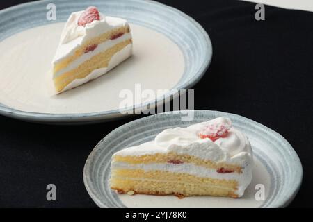 Kleine japanische Erdbeer-Shortcakes auf zwei stilvollen japanischen Tellern, jeweils auf einem schwarzen Tuch auf einem weißen Tisch. Stockfoto