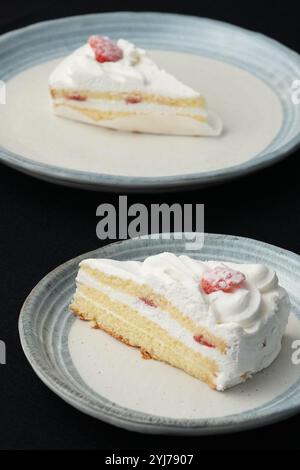 Kleine japanische Erdbeer-Shortcakes auf zwei stilvollen japanischen Tellern, jeweils auf einem schwarzen Tuch auf einem weißen Tisch. Stockfoto