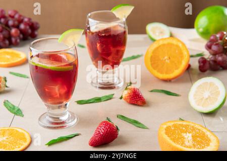 Nahaufnahme von Glasbechern mit hausgemachtem Sommerwein, umgeben von Orangen und Zitronen auf Keramiktisch Stockfoto