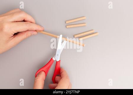 Nahaufnahme der Hand Schere Schneiden Papier Strohschritt im kreativen Prozess DIY schnelle Montage vereinfachte Kinderspielzeug Stockfoto