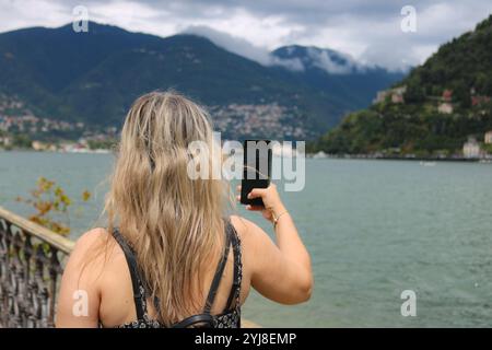 Eine Frau, die Fotos mit einem Handy am See macht Stockfoto