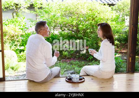 Ehepaar mittleren Alters und Senioren trinken Tee auf der Veranda Stockfoto