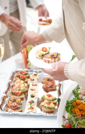 Leute essen Hors d'oeuvres auf einer Hausfeier Stockfoto