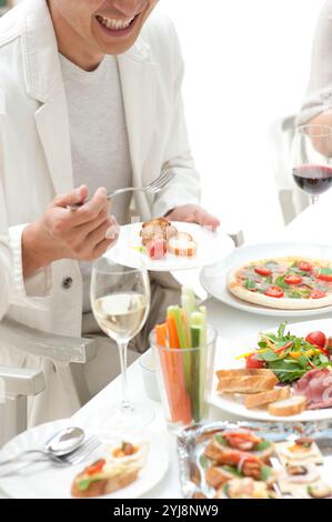 Leute essen Hors d'oeuvres auf einer Hausfeier Stockfoto