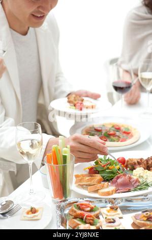 Leute essen Hors d'oeuvres auf einer Hausfeier Stockfoto