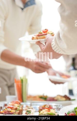 Leute essen Hors d'oeuvres auf einer Hausfeier Stockfoto