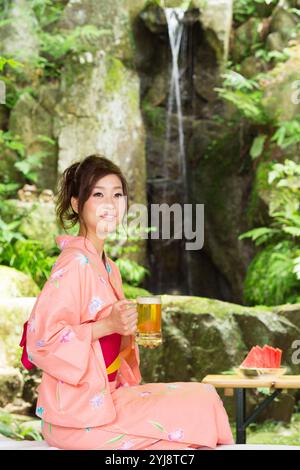 Frau in Yukata, die einen Becher Bier vom Fass hält Stockfoto