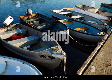 Ruderboote und Jollen stehen an einem ruhigen Sommertag im Hafen an einem Dock in der Rue New Hampshire an Stockfoto