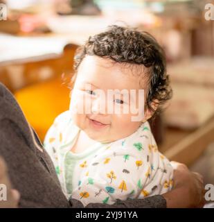 Ein lächelndes viermonatiges Baby, das von ihrer Mutter gehalten wird Stockfoto