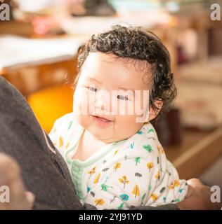 Ein lächelndes 4 Monate altes Baby wird gehalten Stockfoto