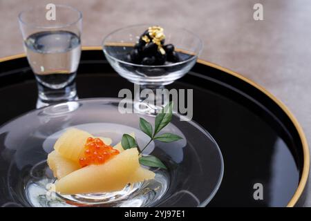 Glas-Sake-Becher-Set mit ein paar Heringsrogen und schwarzen Bohnen serviert in Glasgefäßen Stockfoto