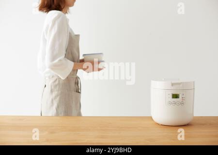 Frau kreuzt sich mit Reiskocher und Tupperware Stockfoto