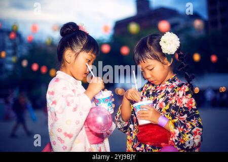 Ein Mädchen in Yukata isst rasiertes Eis, das von einem Festivalstand gekauft wurde Stockfoto