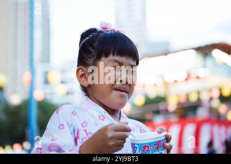 Mädchen in Yukata mit Kopfschmerzen, weil sie rasiertes Eis isst Stockfoto