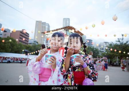 Ein Mädchen in Yukata isst rasiertes Eis vor der Yagura Stockfoto