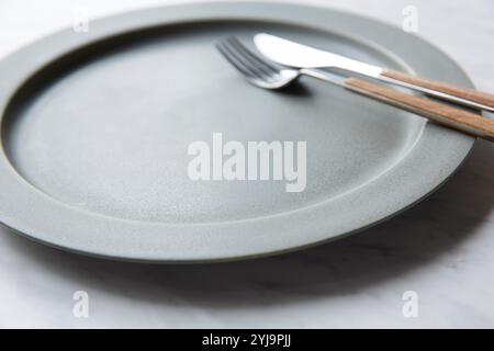 Graue Teller und Besteck auf Marmor Stockfoto