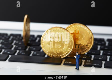 Bitcoin und Miniatur stehen oben auf der Tastatur Stockfoto